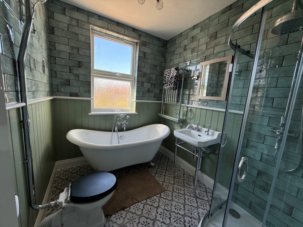 Lot: 132 - THREE-BEDROOM TERRACE HOUSE - Bathroom with roll edge bath shower and window to rear